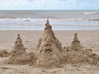 sand castle with ocean behind, and cursive JTL watermark in lower right corner