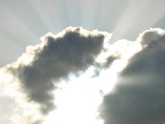 sun shining behind clouds with light beams coming out, a tree just out of frame in the bottom right corner and a cursive connected and encircled JTL in t he bottom left corner